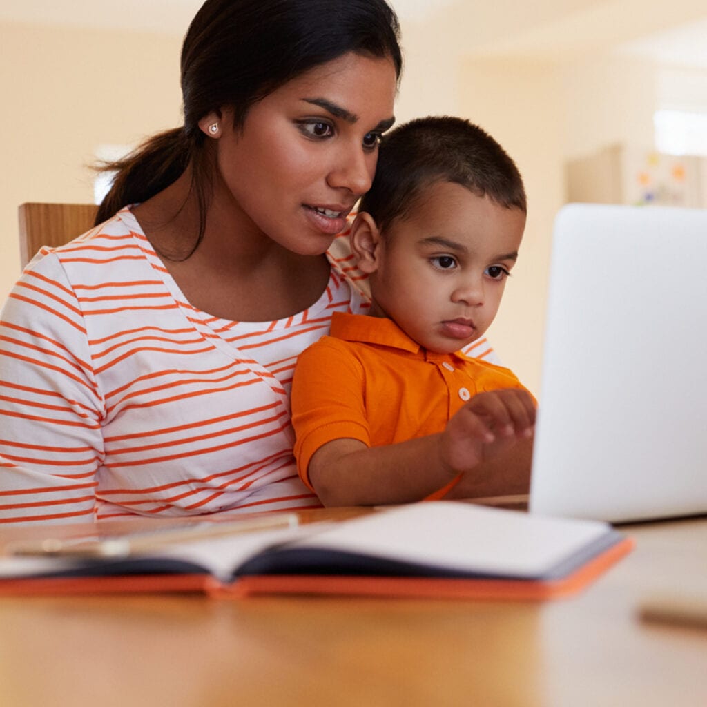 Mother And Son In Kitchen Looking At Laptop Together