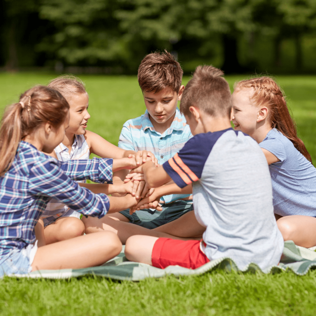 Kids Socializing and playing a game at the park on a picnic blanket.