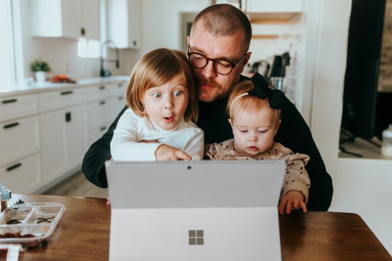 Young dad plays with his two children on their tablet computer.
